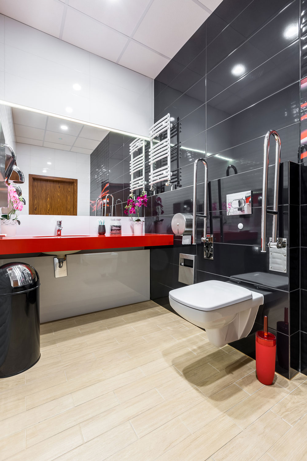 renovation-salle-de-bains-pmr-design-antony.jpg Salle de bains PMR design avec carrelage noir, plan vasque rouge et barres de maintien installée à Antony par A.M Rénovations.